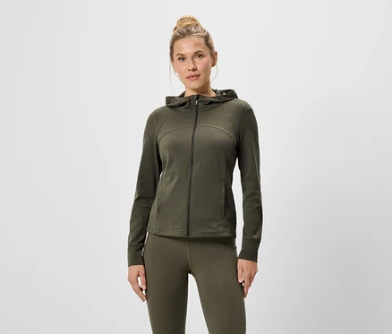 Frau trägt eine olivgrüne Kapuzenjacke mit Reißverschluss und Leggings.