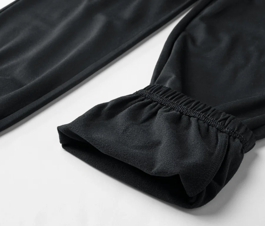Nahaufnahme einer schwarzen Jogginghose mit elastischem Bund am Beinabschluss auf einem weißen Hintergrund.
