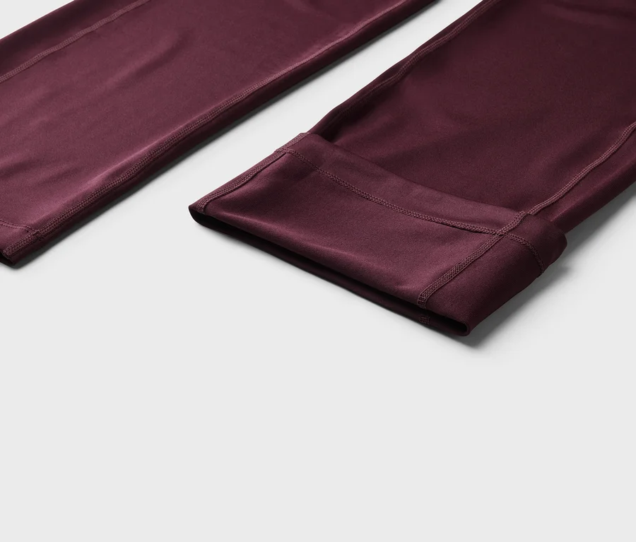 Nahaufnahme von weinroten Leggings, wobei ein Hosenbein hochgekrempelt ist.