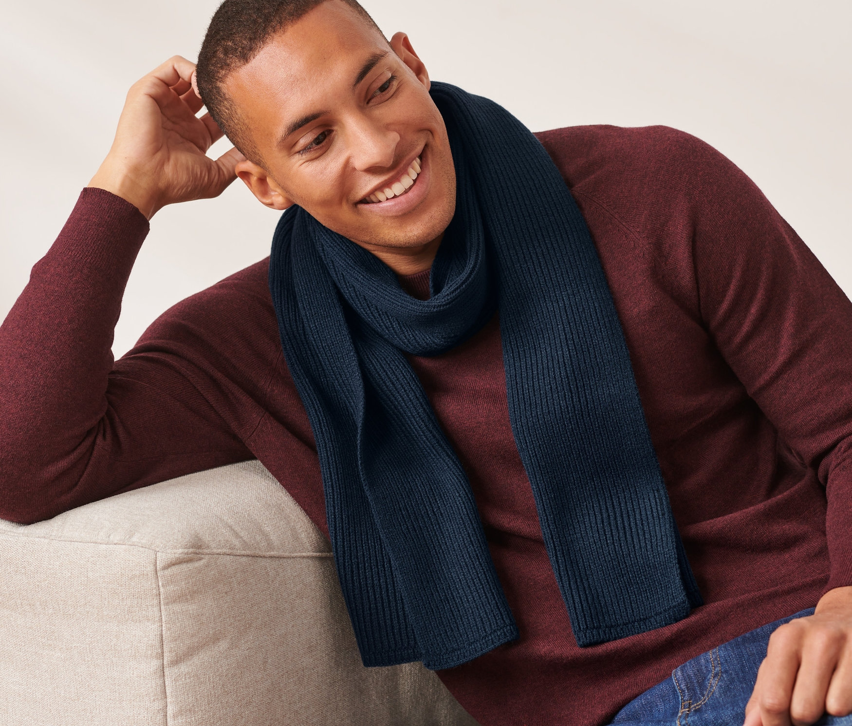 Mann sitzt auf Couch und trägt einen navyblauen Strickschal.