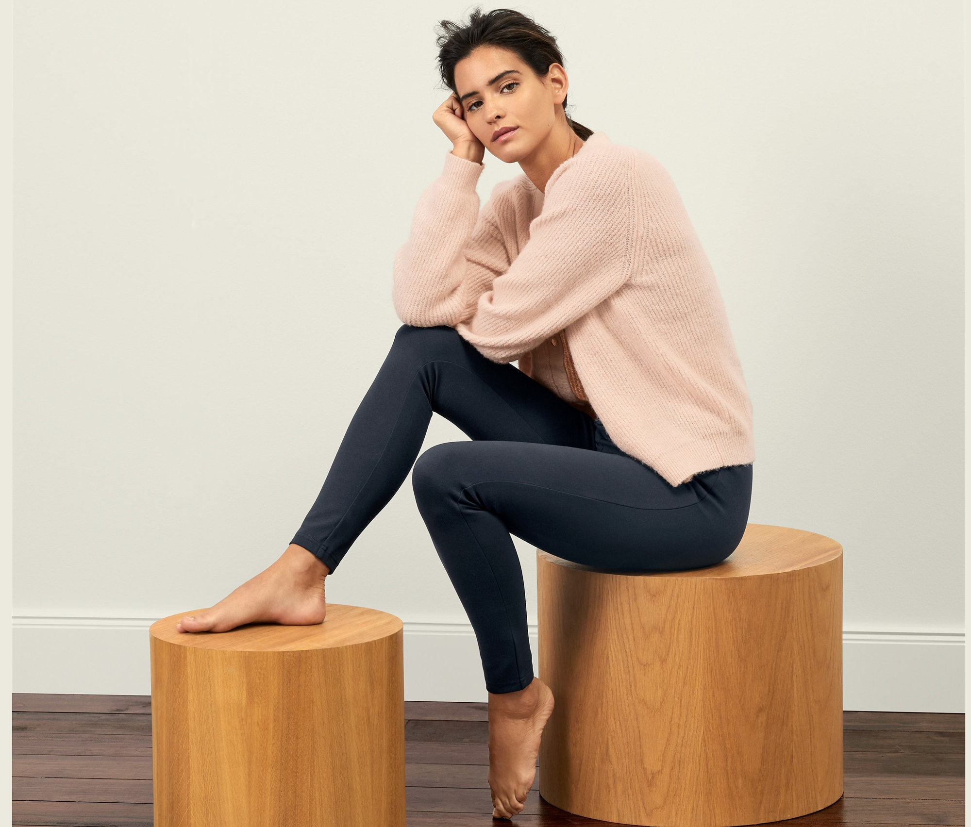 Frau sitzt auf einem Holzhocker und trägt Leggings aus Heavy-Jersey.