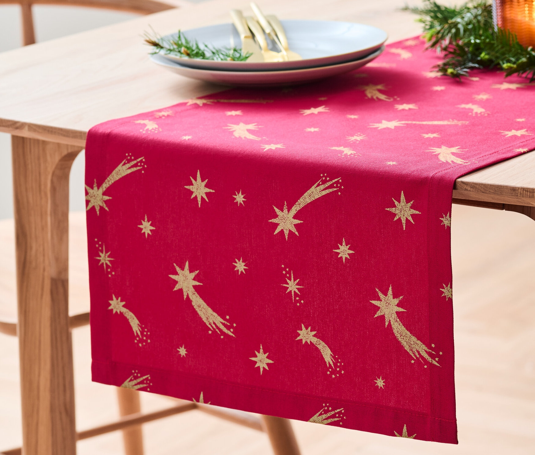 Auf einem Holztisch liegt ein Baumwoll-Tischläufer mit Sternenmuster.
