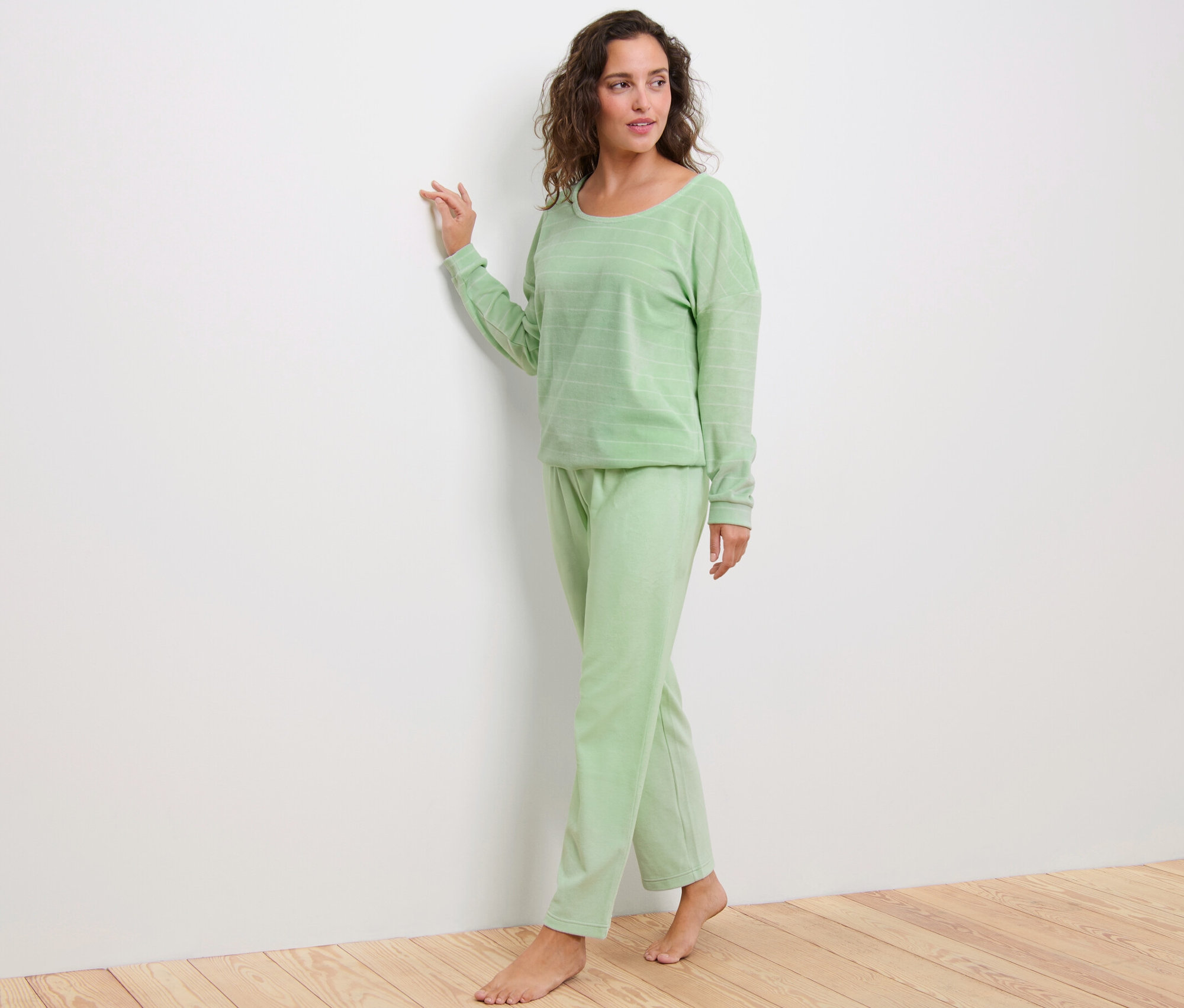 Frau steht und trägt einen grünen Nicki-Pyjama.