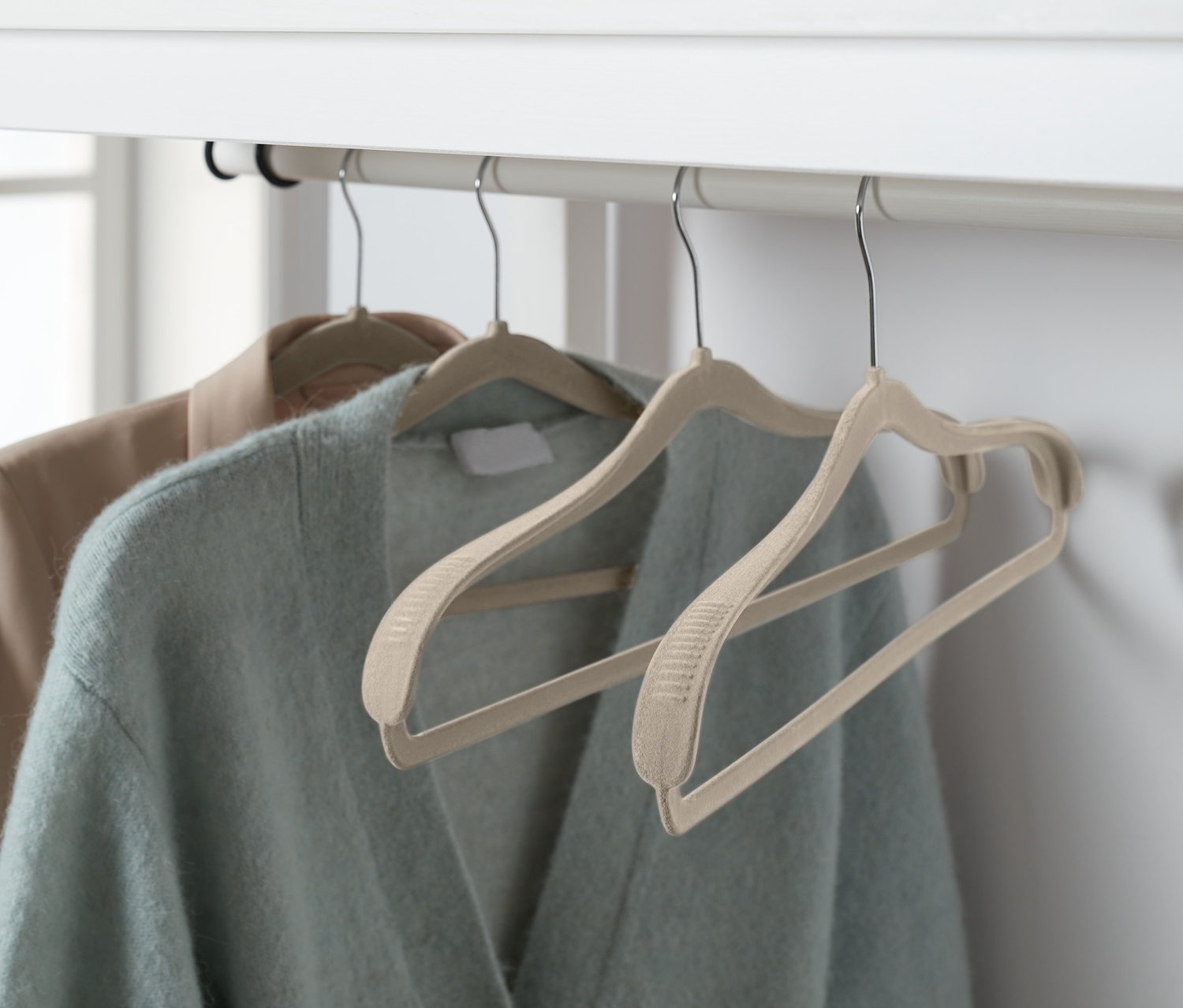 Zwei Jacken hängen auf 4 Kleiderbügel mit Schulterverstärkung an einem weißen Gestell.