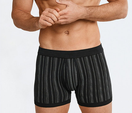 Oberkörperfreier Mann trägt schwarze SCHIESSER Feinripp-Shorts mit weißen Längsstreifen, die Hände gefaltet.