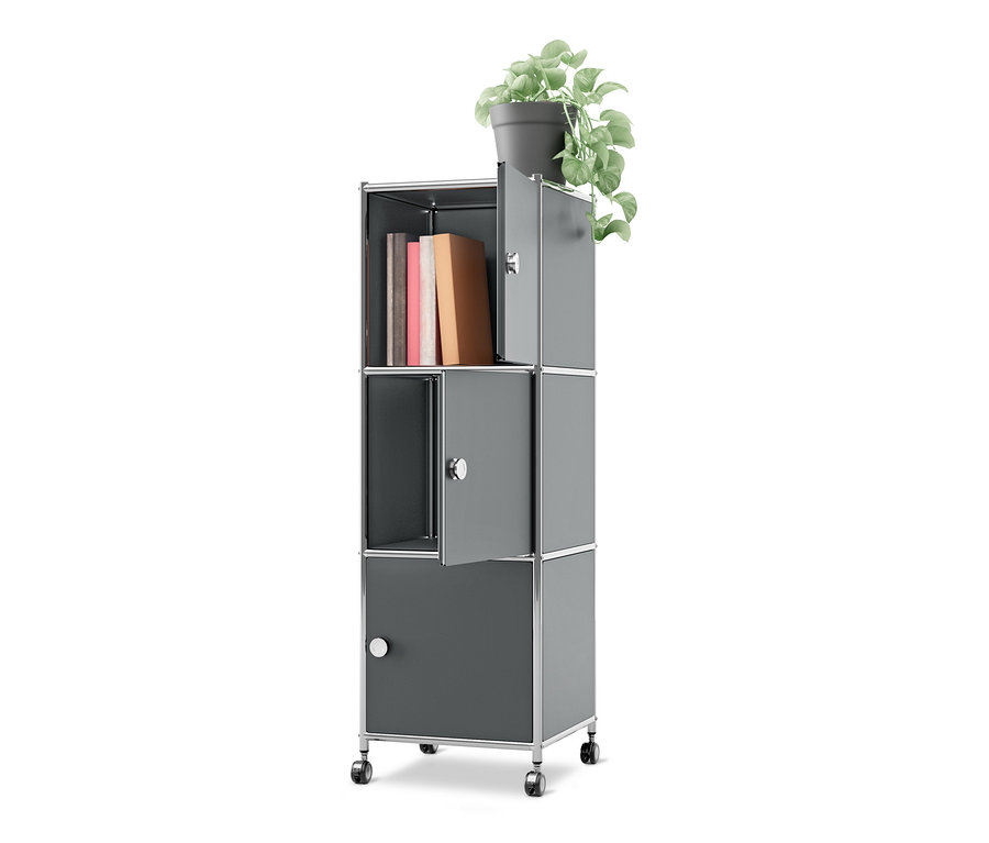 Grauer Rollcontainer Metall »CN3« mit 3 Türen auf Rollen, mit Büchern in einem offenen Fach und einer Topfpflanze oben. Zwei Türen sind leicht geöffnet.