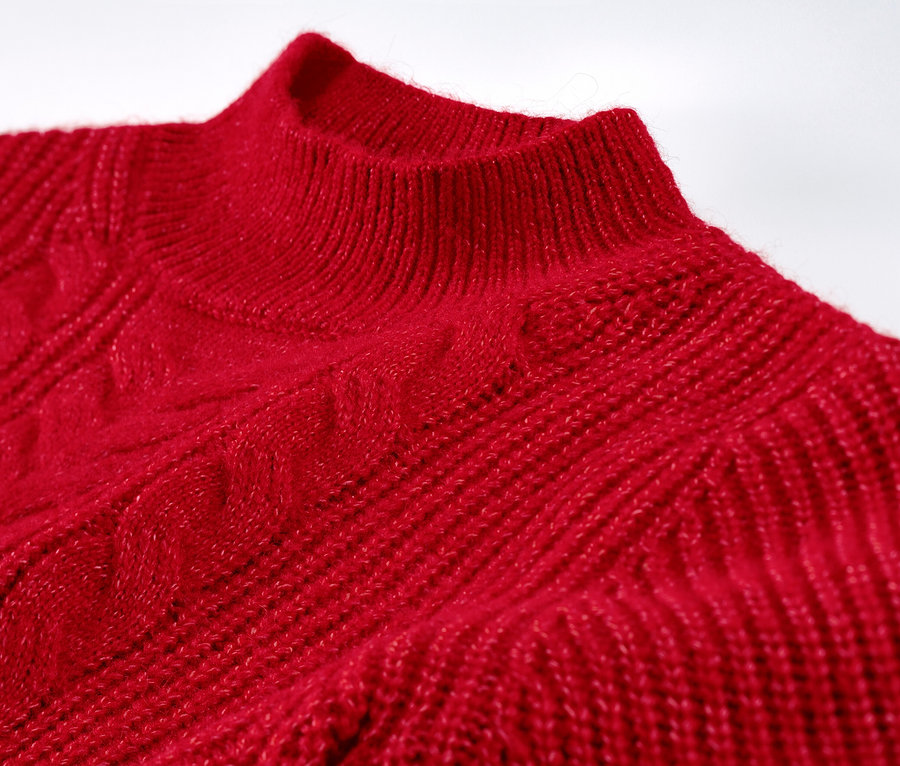 Detailansicht eines roten Grobstrickpullovers mit Zopfmuster.