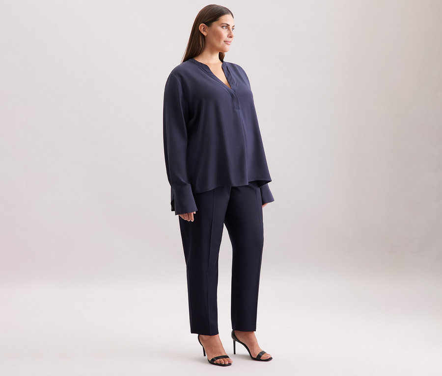 Frau steht seitlich, trägt eine navy Seidensticker Viskose-Tunika, Hose und Sandalen.