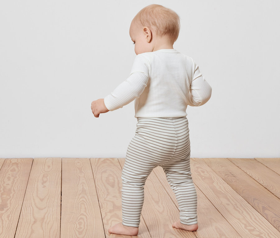 Kleinkind geht auf einem Holzboden und trägt eine gestreifte 5 Kinder-Leggings.