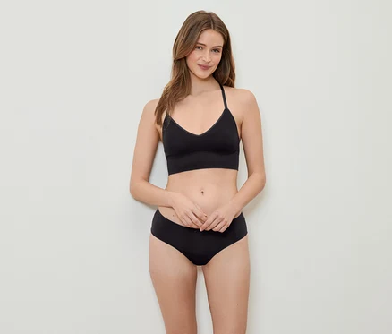 Eine Frau posiert in einem schwarzen Sport-BH und Unterhose.