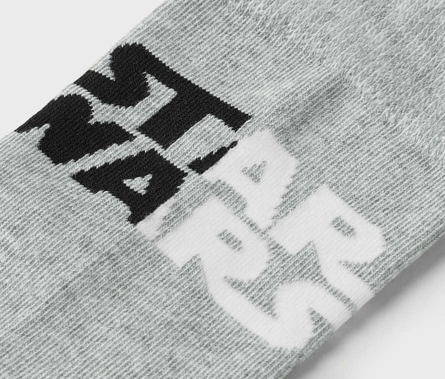 Detailaufnahme einer grauen Socke mit schwarzer und weisser Beschriftung.