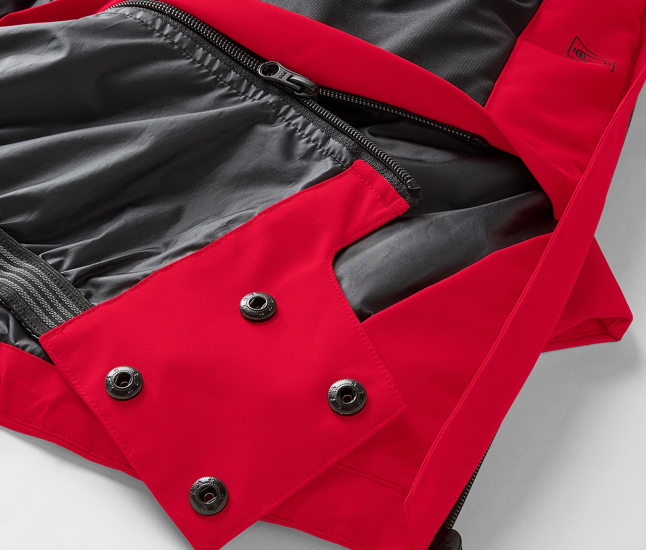 Detailaufnahme einer roten Jacke mit schwarzem Futter und Druckknöpfen.