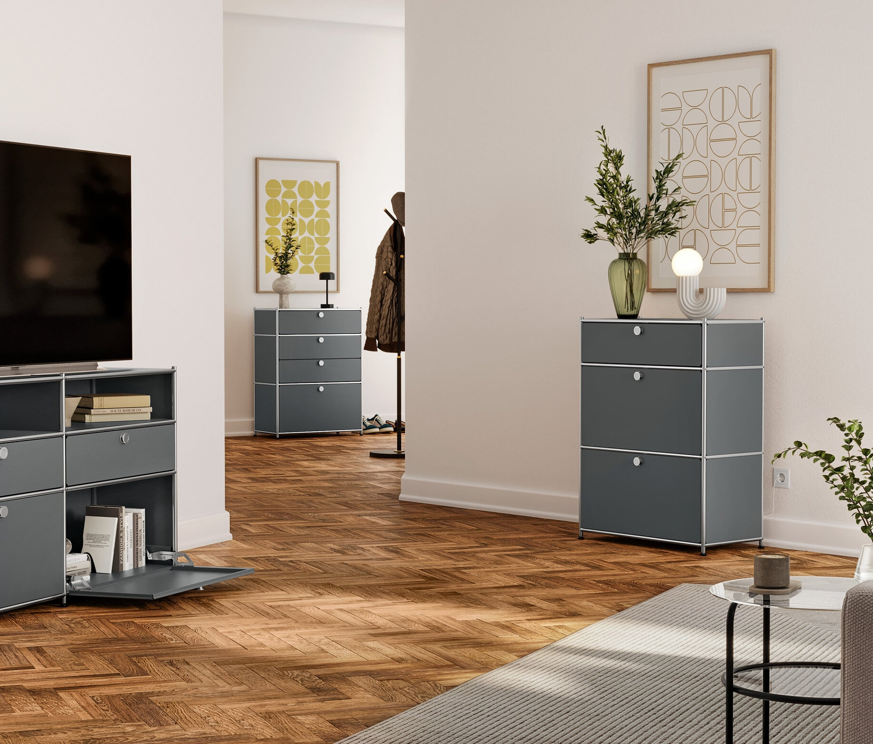 Wohnzimmer mit Fernseher auf grauer Metallkommode mit Schubladen und offenen Regalen. Im Hintergrund graue Kommode mit drei Schubladen und eine weitere im Flur.