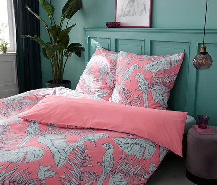 Vier Renforcé-Bettwäsche-Sets Tropical Rose in verschiedenen Größen auf einem Bett.