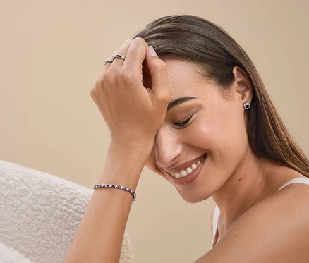 Lächelnde Frau mit Ring, Armband und Ohrringen.