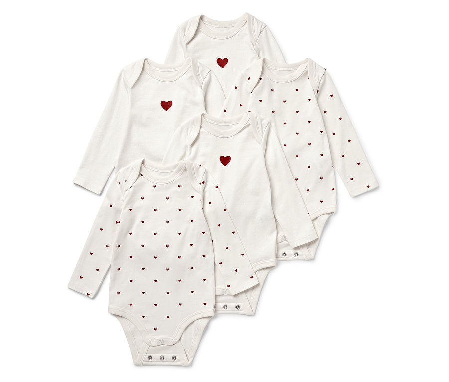 Fünf weiße Baby-Langarmbodys, einige mit einem roten Herz in der Mitte, andere mit einem roten Herzmuster.