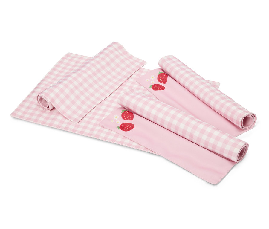 Auf einem weißen Hintergrund liegen eine rosa-weiß karierte Decke und zwei rosa Stoffe mit Erdbeermotiven, die teilweise aufgerollt sind.