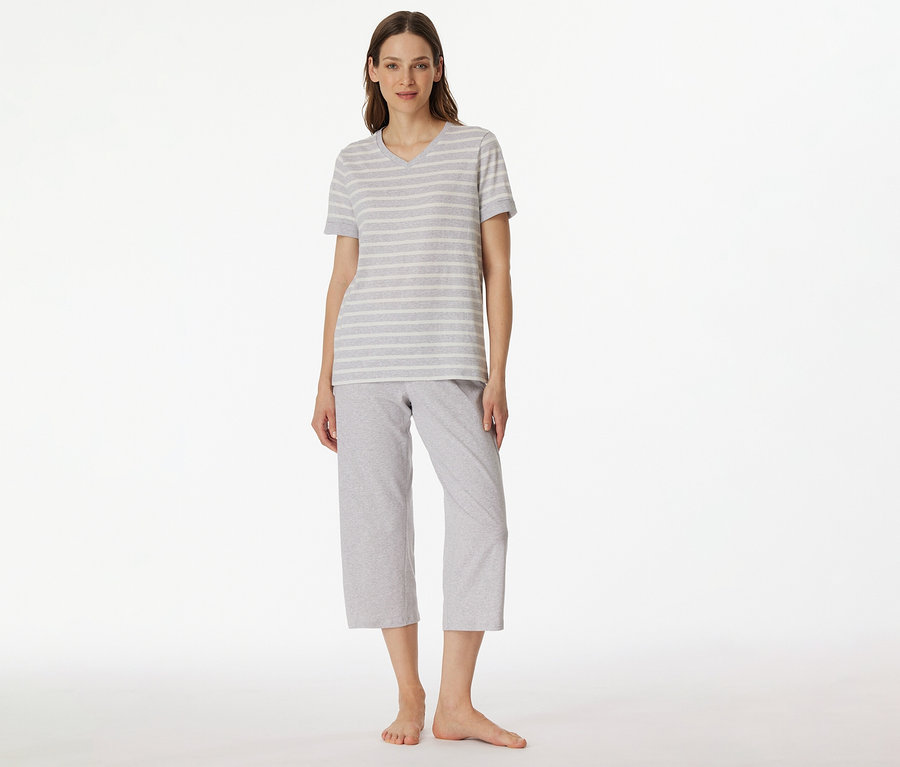 Frau trägt SCHIESSER 3/4-Pyjama mit grau-weiß gestreiftem T-Shirt und grauer 3/4-Hose vor weißem Hintergrund.