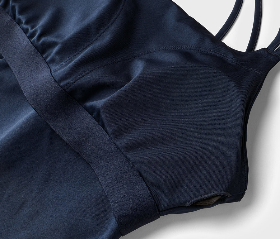 Nahaufnahme eines marineblauen Sportoberteils mit Trägern und integriertem BH auf weißem Grund.