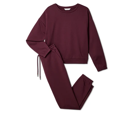 Burgunderfarbenes Set aus Sweatshirt und Jogginghose liegt auf weißem Grund.