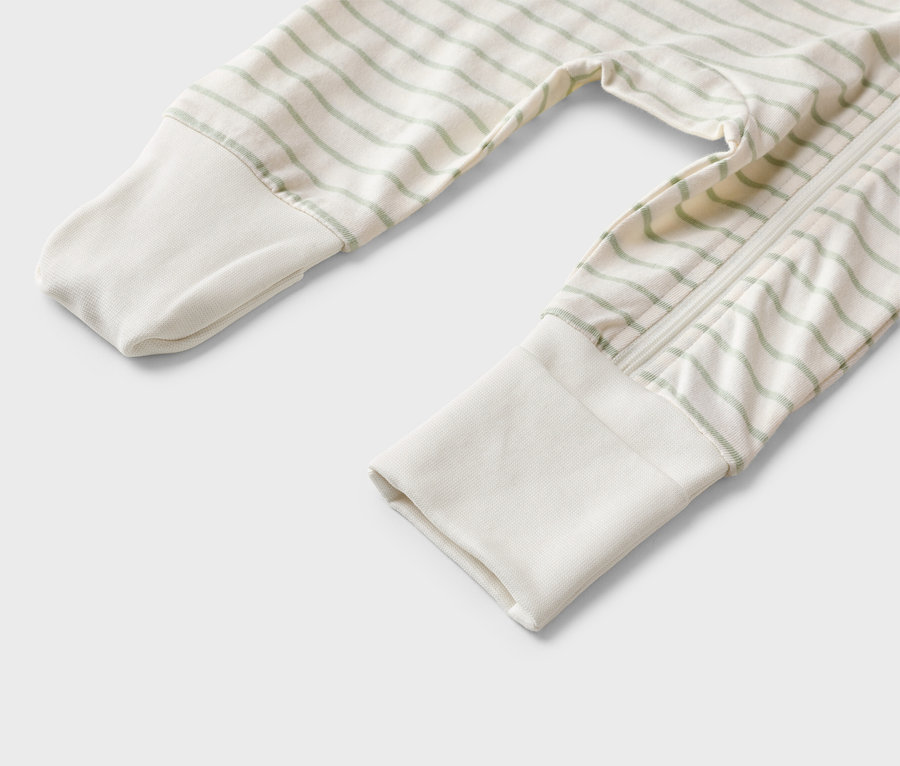 Nahaufnahme eines hellen Strampelanzugs mit grünen Streifen und einem Reißverschluss.