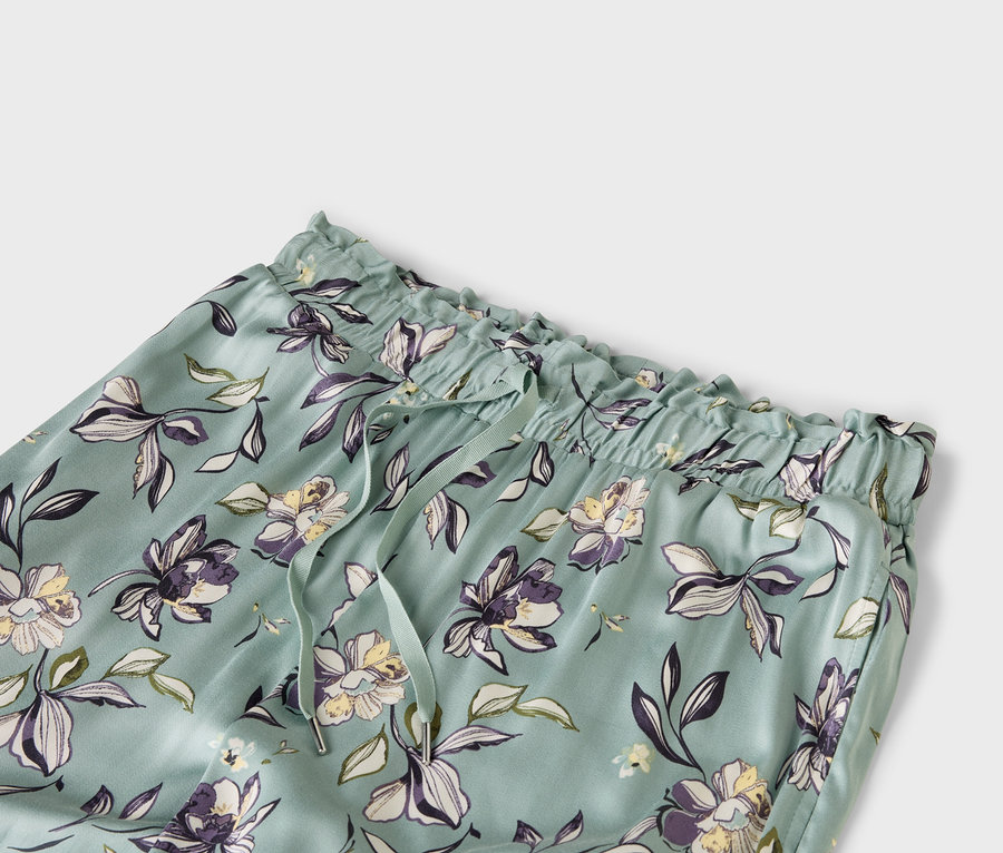 Nahaufnahme einer hellblauen Hose mit Blumenmuster, elastischem Bund und Kordelzug.