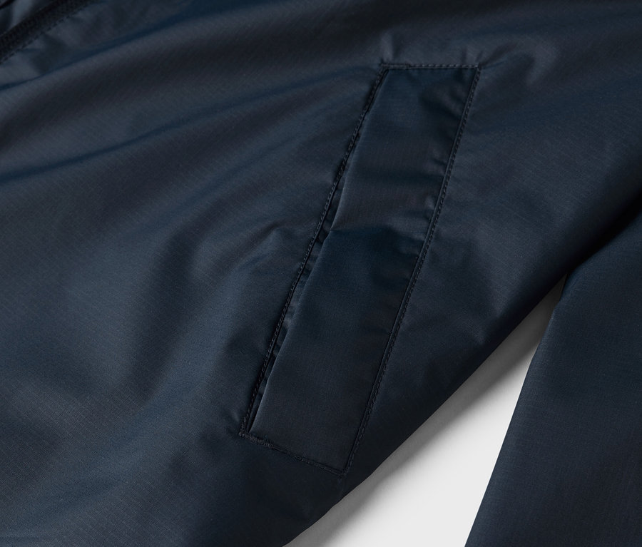 Detailaufnahme einer marineblauen Jacke mit einer aufgesetzten Tasche.