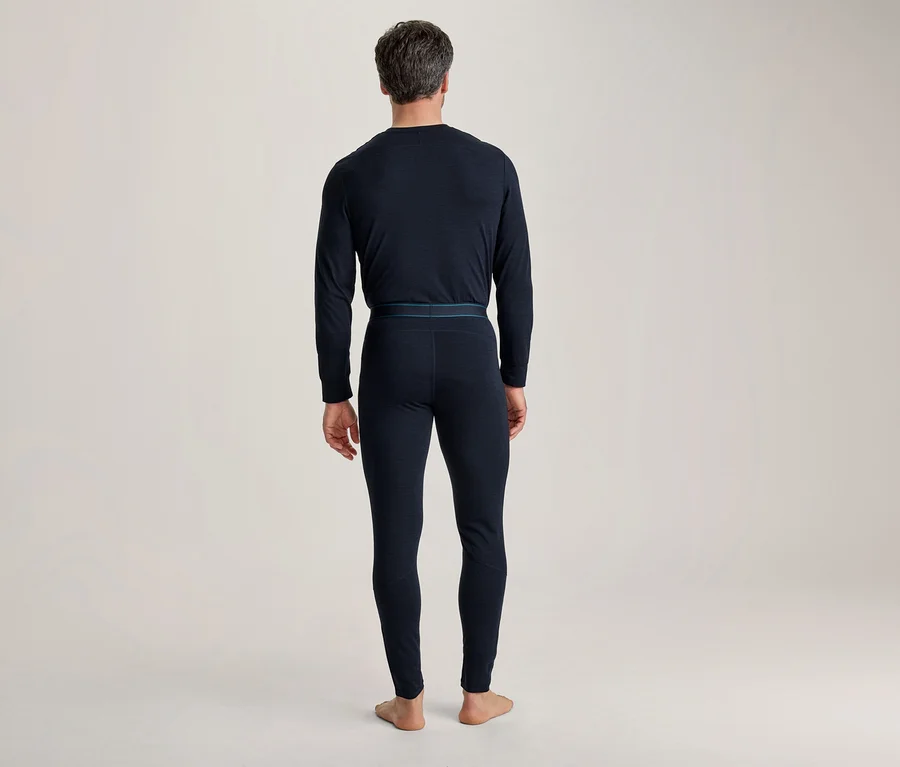 Mann von hinten, der eine dunkelblaue, langärmelige Thermounterwäsche und lange Thermohosen mit einem dünnen blauen Bund trägt.