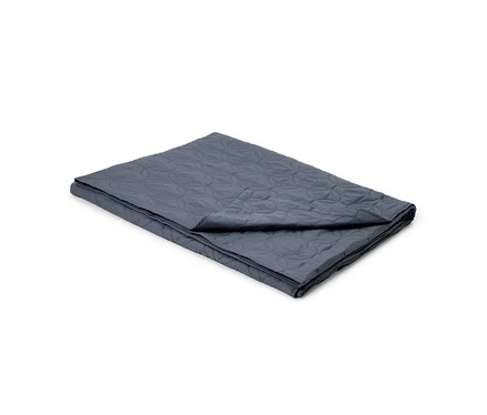 Eine dunkelgraue, gefaltete Steppdecke mit einem Muster aus ineinandergreifenden Kreisen.