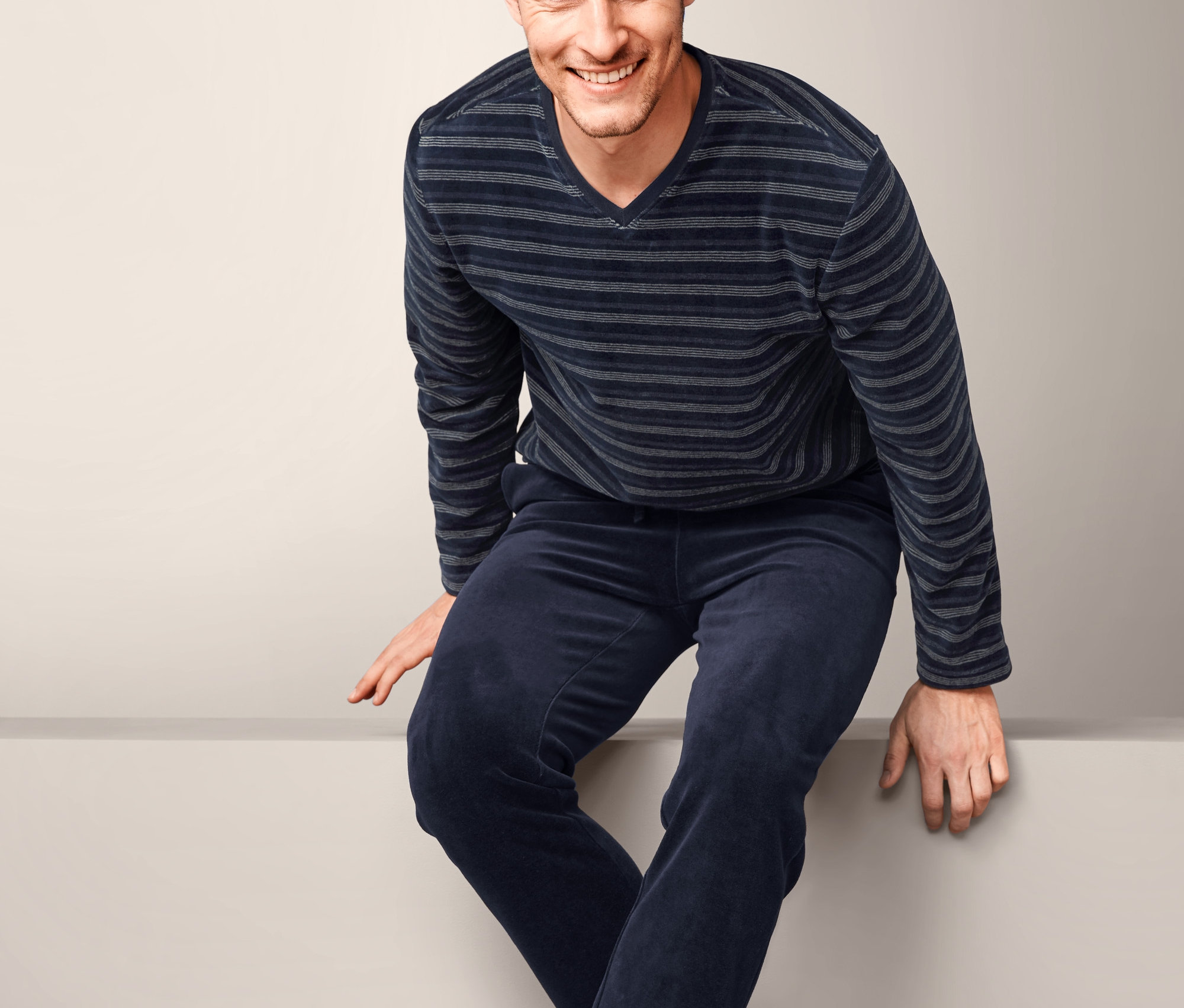 Mann sitzt und trägt einen Nicki-Pyjama.