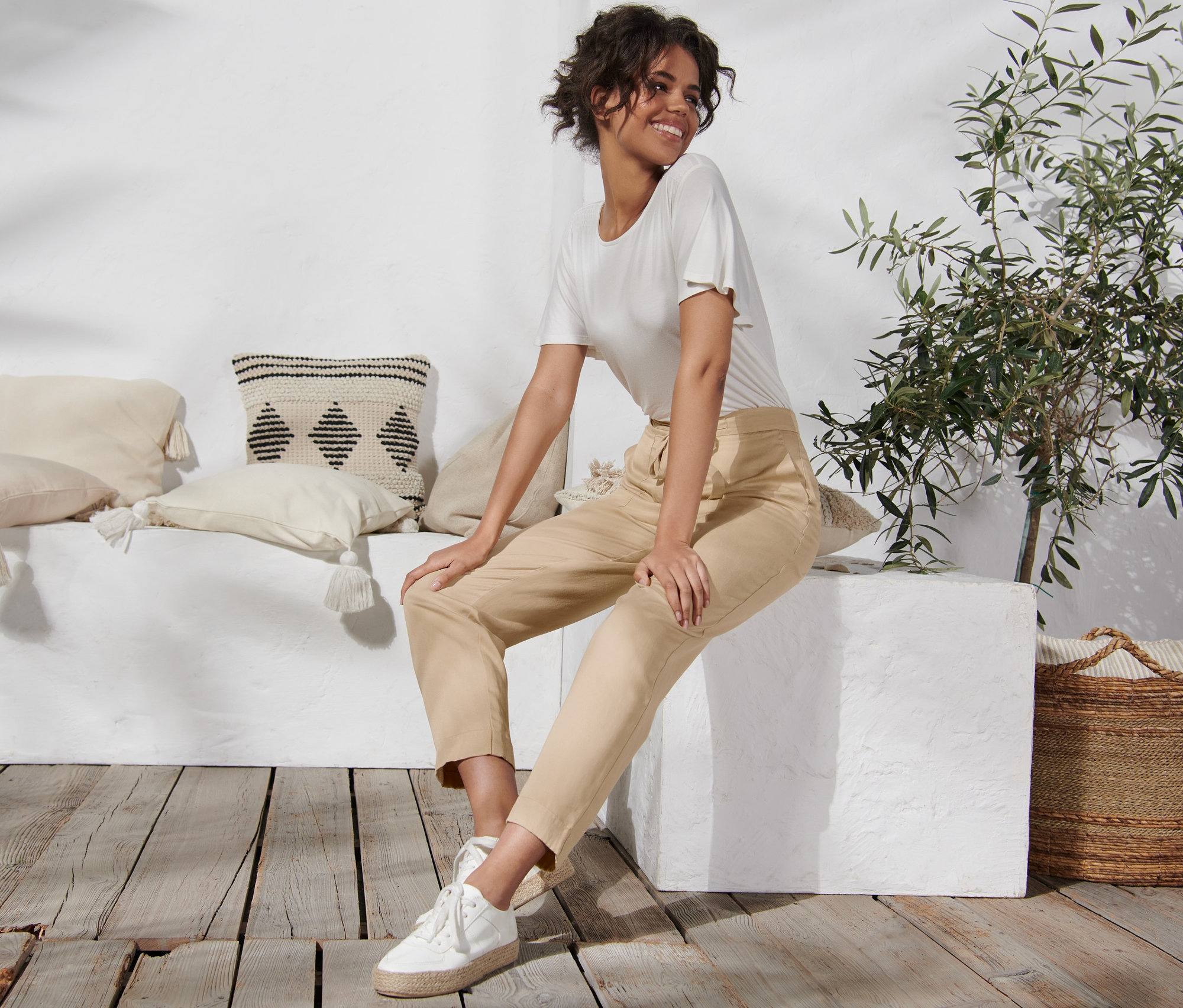 Frau sitzt auf einem weißen Block und trägt eine Hose aus Leinenmix.