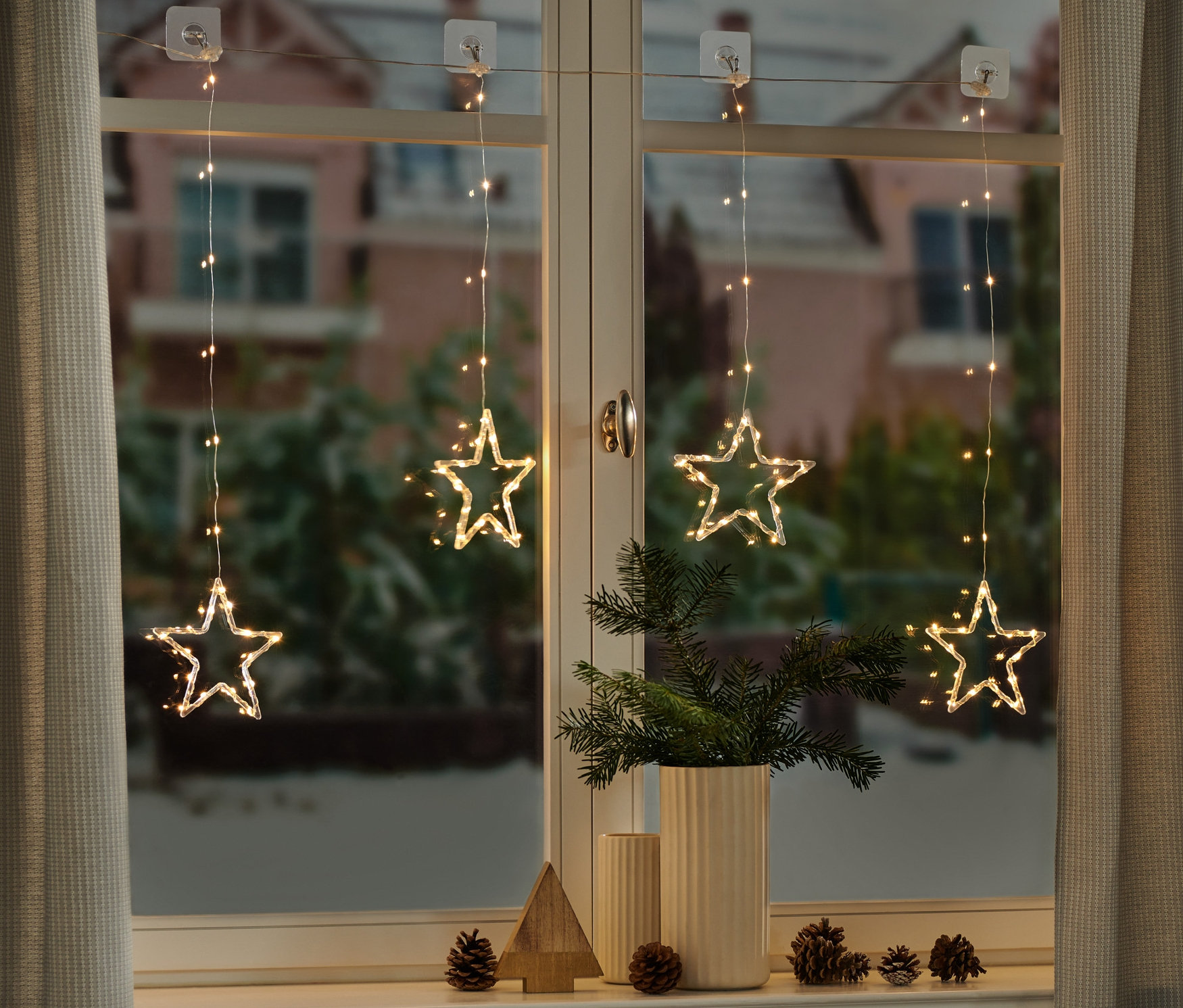 Vier LED-Lichtervorhänge mit Sternen hängen am Fenster.