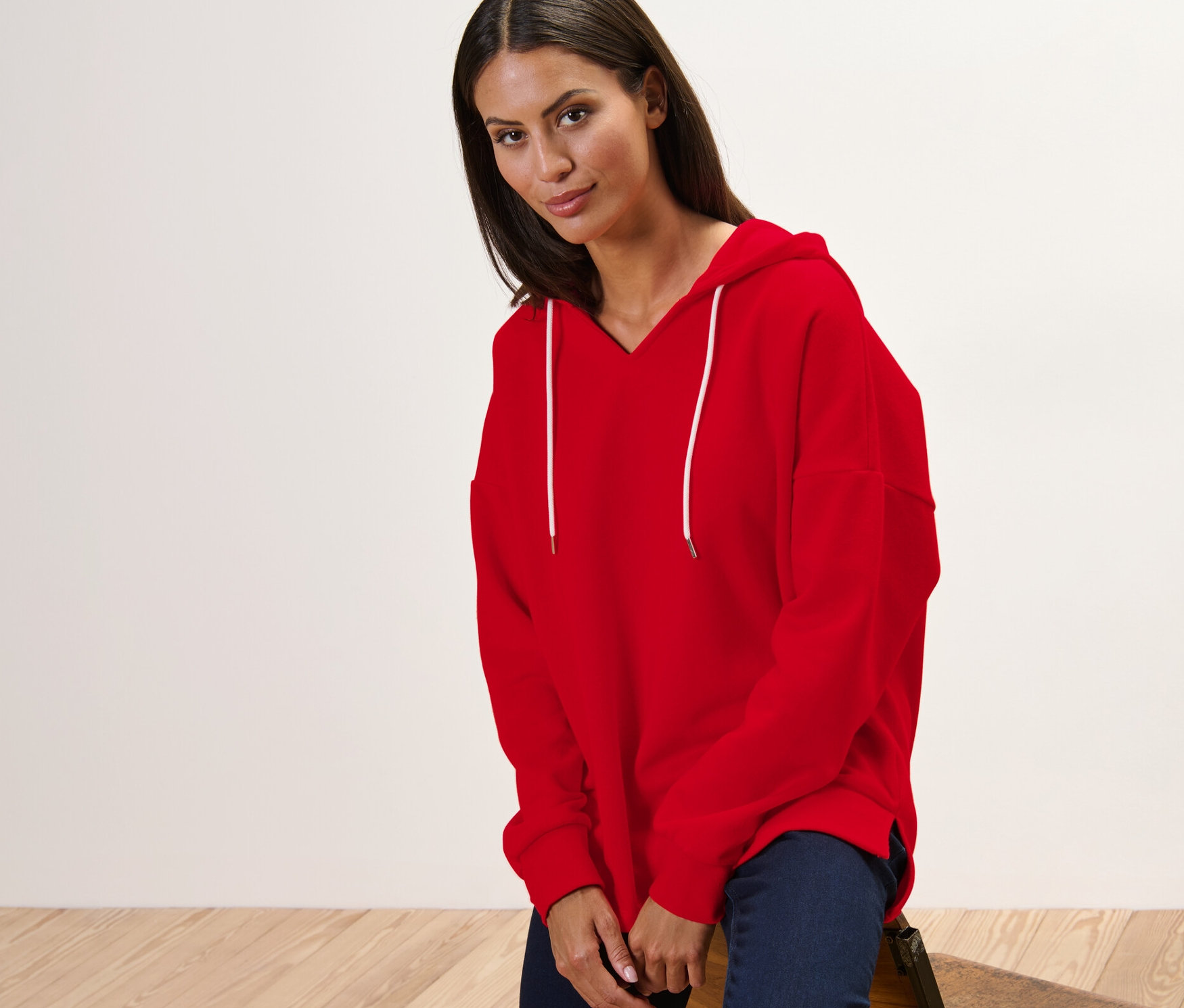 Frau sitzt auf einem Stuhl und trägt einen roten Hoodie.