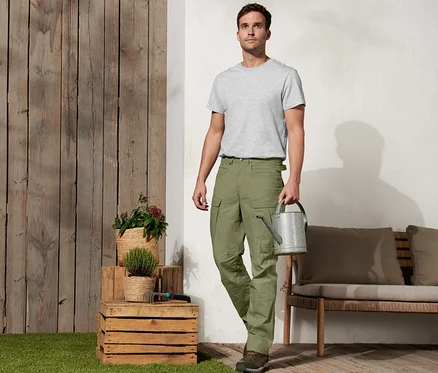 Mann hält Gießkanne und trägt eine Outdoorhose »Workwear«.