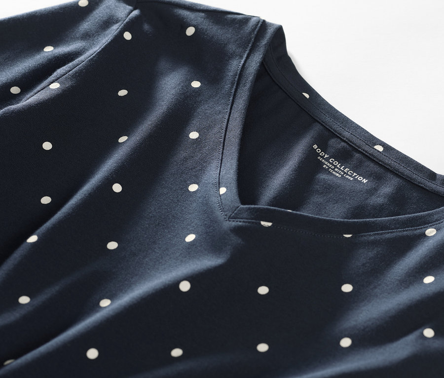 Detailaufnahme eines Nachthemds mit dunkelblauem Hintergrund und weißen Punkten.