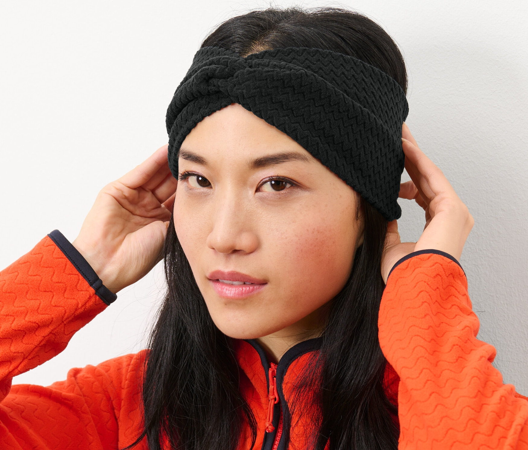 Frau richtet ihr schwarzes Fleecestirnband.