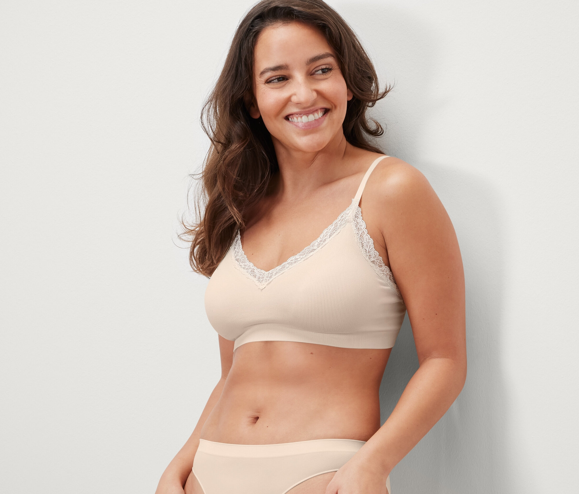 Lächelnde Frau trägt ein nahtloses Bustier in Creme mit Spitze.