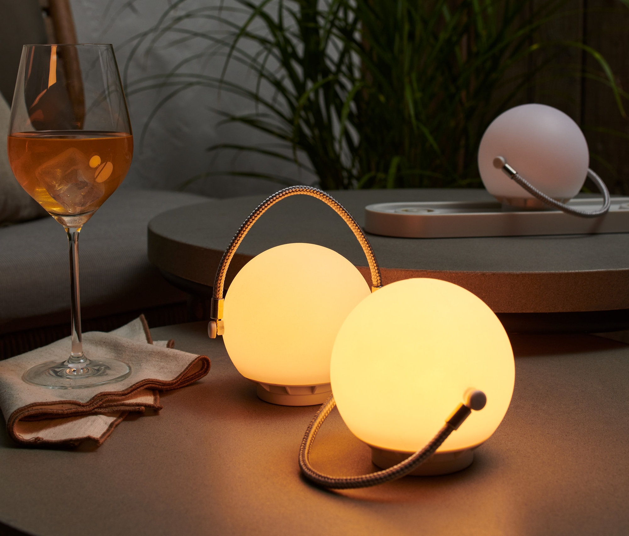 Auf einem Tisch steht ein Akku-Tischleuchten-Set neben einem Getränk.