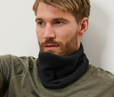 Mann mit braunem Haar sitzt und trägt einen schwarzen Fleecekragen.