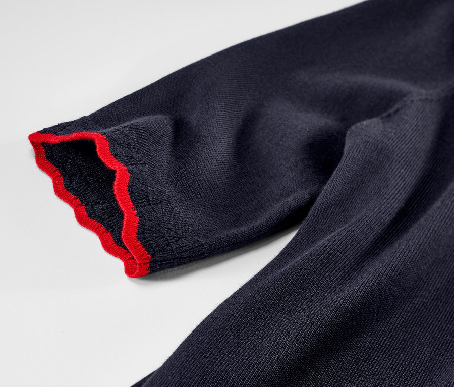 Detailaufnahme eines dunkelblauen Feinstrickpullovers mit roter Bordüre.