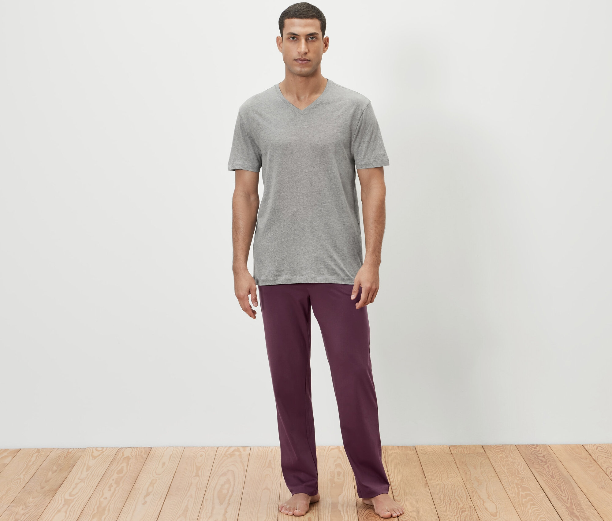 Mann trägt ein graues T-Shirt und eine weinrote Pyjamahose.