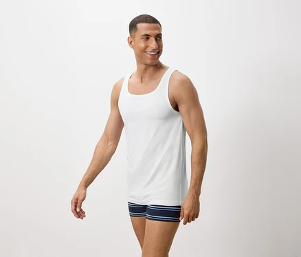 Mann lächelt und trägt ein weißes Tanktop und blaue gestreifte Boxershorts.