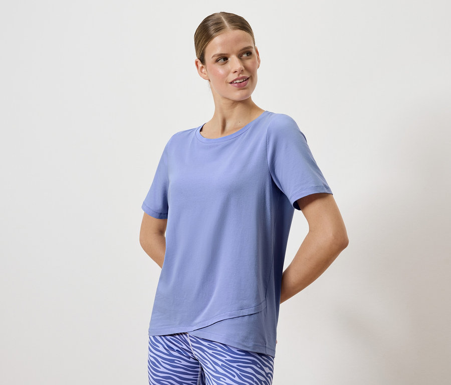 Frau posiert in einem blauen T-Shirt und einer Hose mit Tiermuster.