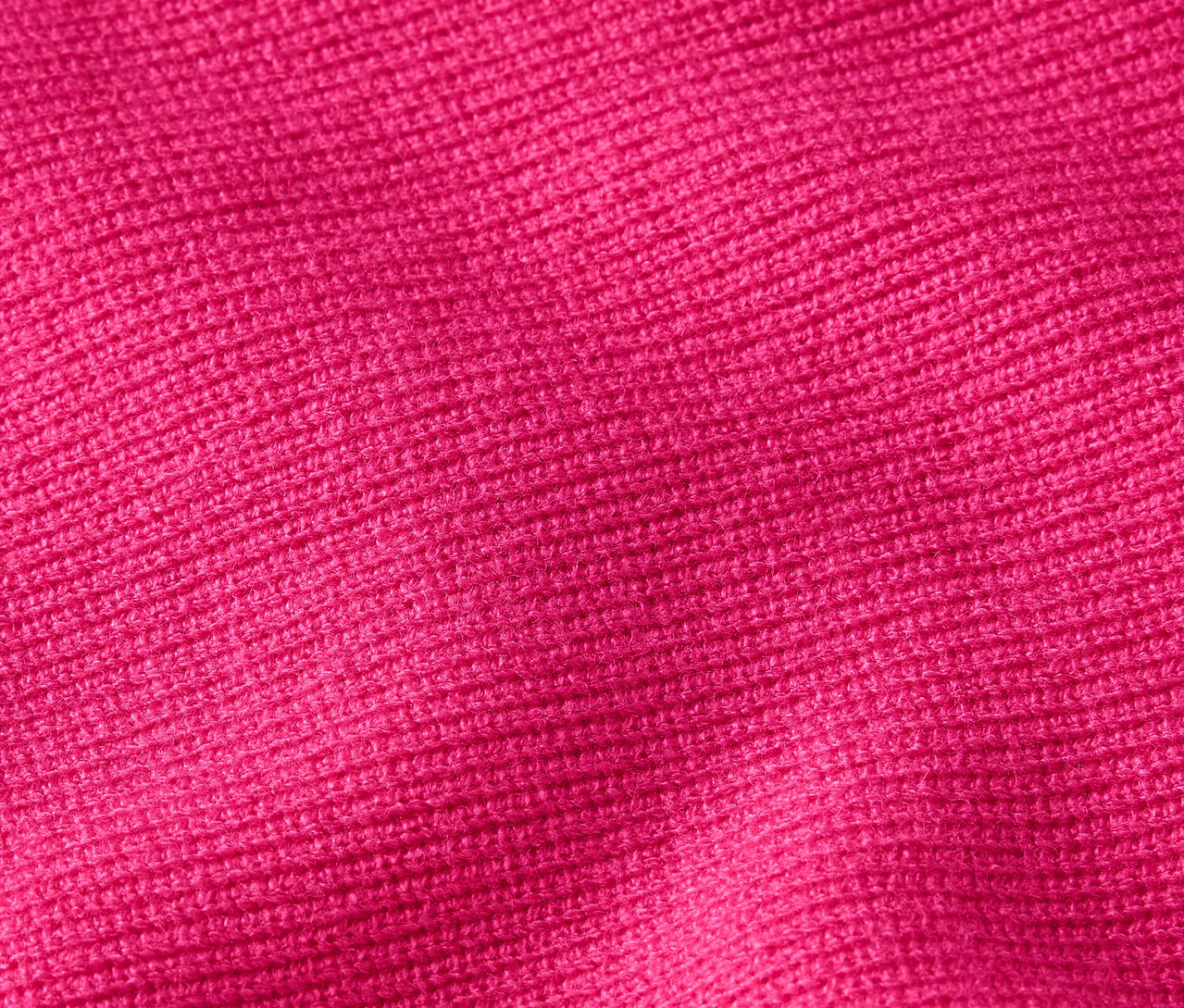 Nahaufnahme der Textur eines Strickstoffs in leuchtendem Pink.