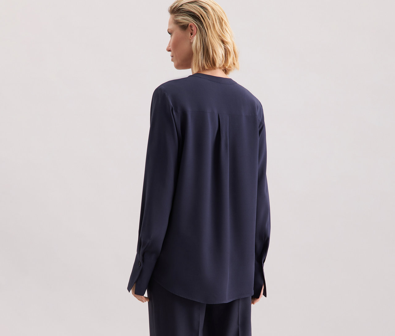 Frau trägt eine marineblaue Seidensticker Tunika aus Viskose, von hinten gesehen.