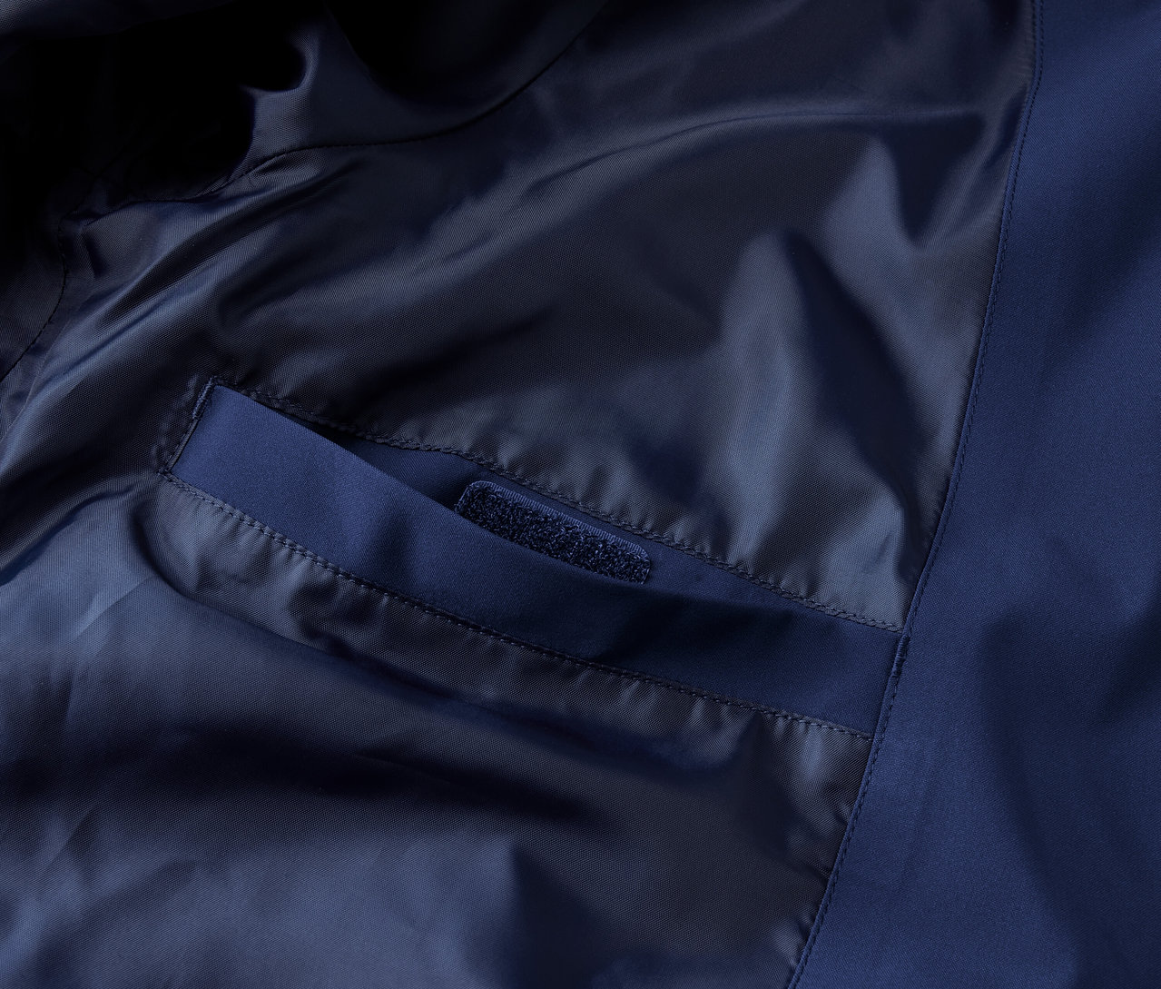 Detailaufnahme einer blauen Funktions-Outdoorjacke mit Innentasche.