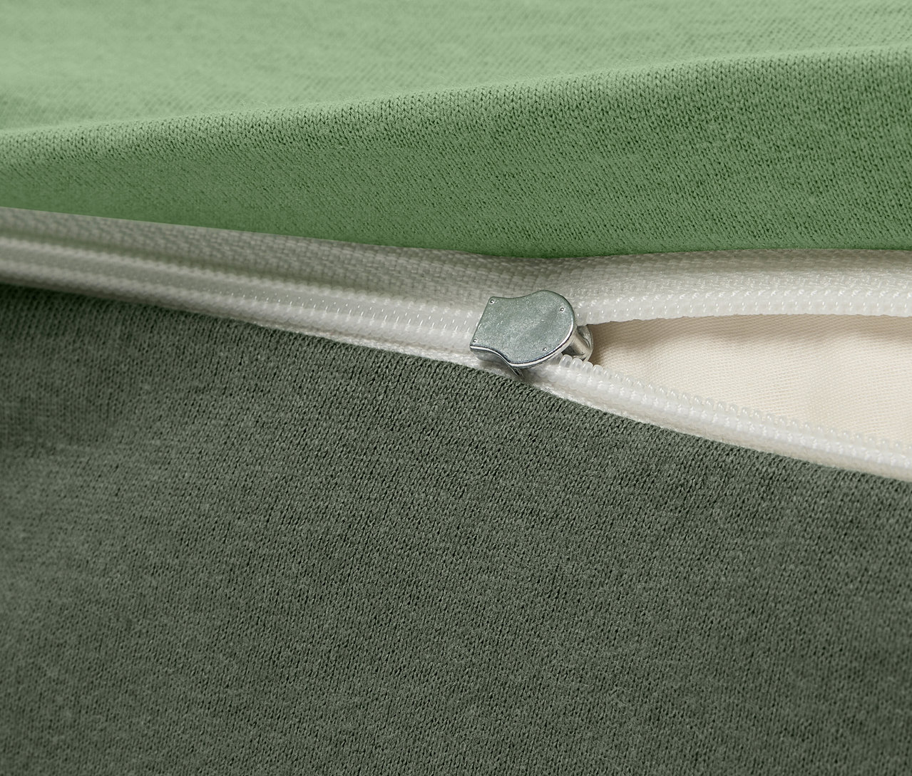 Detailaufnahme eines grün-grauen Stoffbezugs mit Reißverschluss.