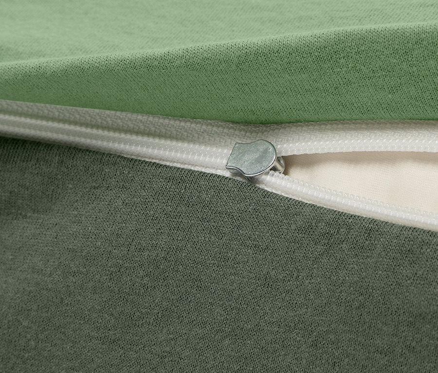 Detailaufnahme eines grün-grauen Stoffbezugs mit Reißverschluss.