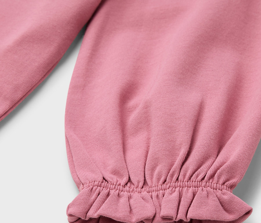 Detail eines rosa Ärmels mit Rüschen.