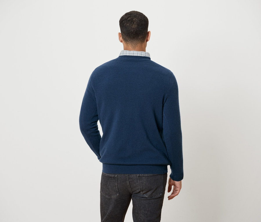 Mann mit dem Rücken zur Kamera trägt einen blauen Pullover und Jeans.